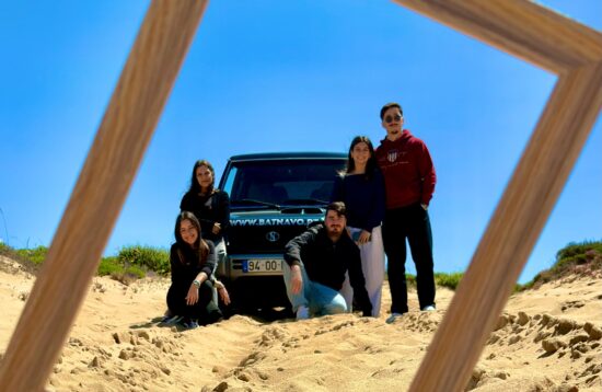 Foto de um grupo de amigos muito felizes e divertidos, em frente a um jipe 4x4, numa paisagem off-road do Cabo Espichel. À frente do grupo, uma moldura decorativa que destaca o momento de celebração e amizade durante o passeio.